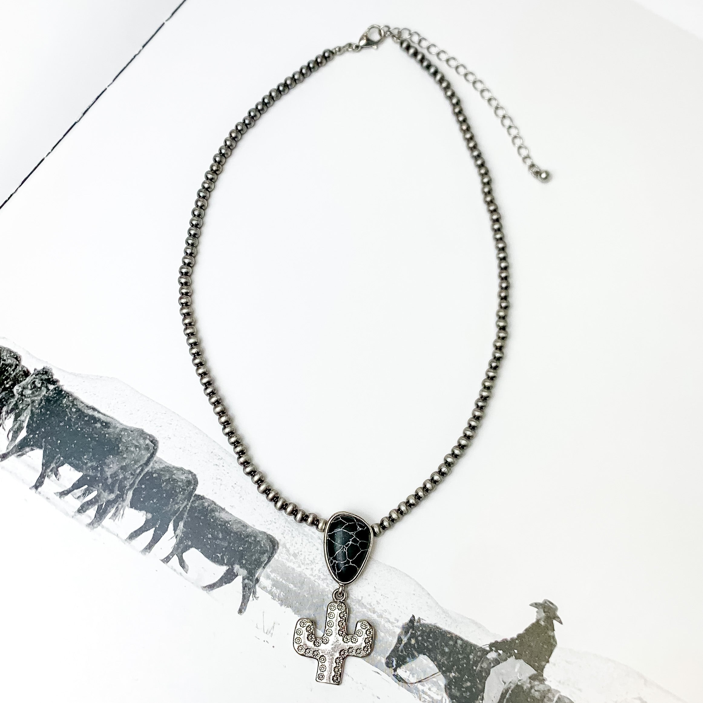 Cactus Queen Faux Navajo Silver Tone Necklace with Stone in Black. Pictured on a white page with a western scone printed on the page.