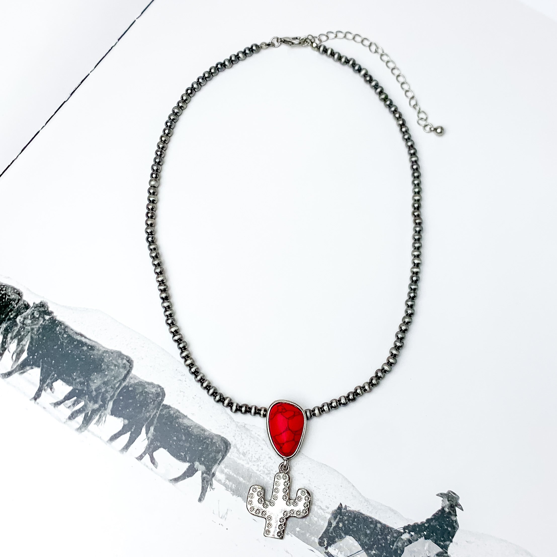 Cactus Queen Faux Navajo Silver Tone Necklace with Stone in Red. Pictured on a white background with a western scene on the background.