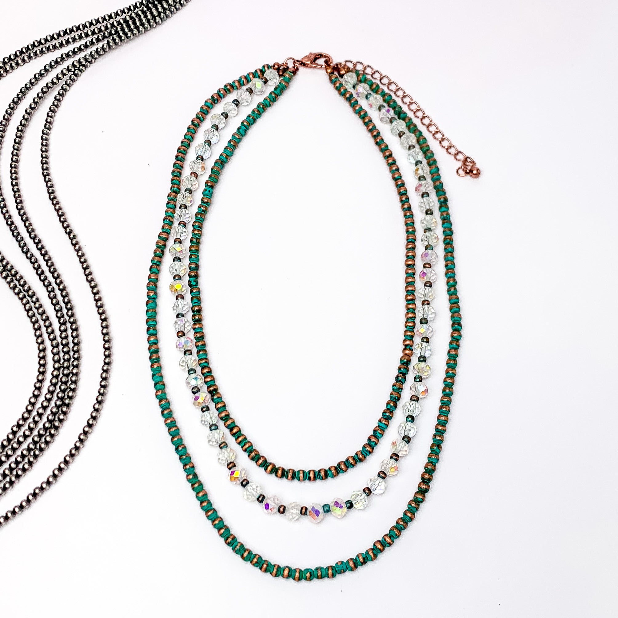 Wild Western Faux Navajo Three Strand Pearl Necklace in Patina Tone. Pictured on a white background with beads to the left for decoration