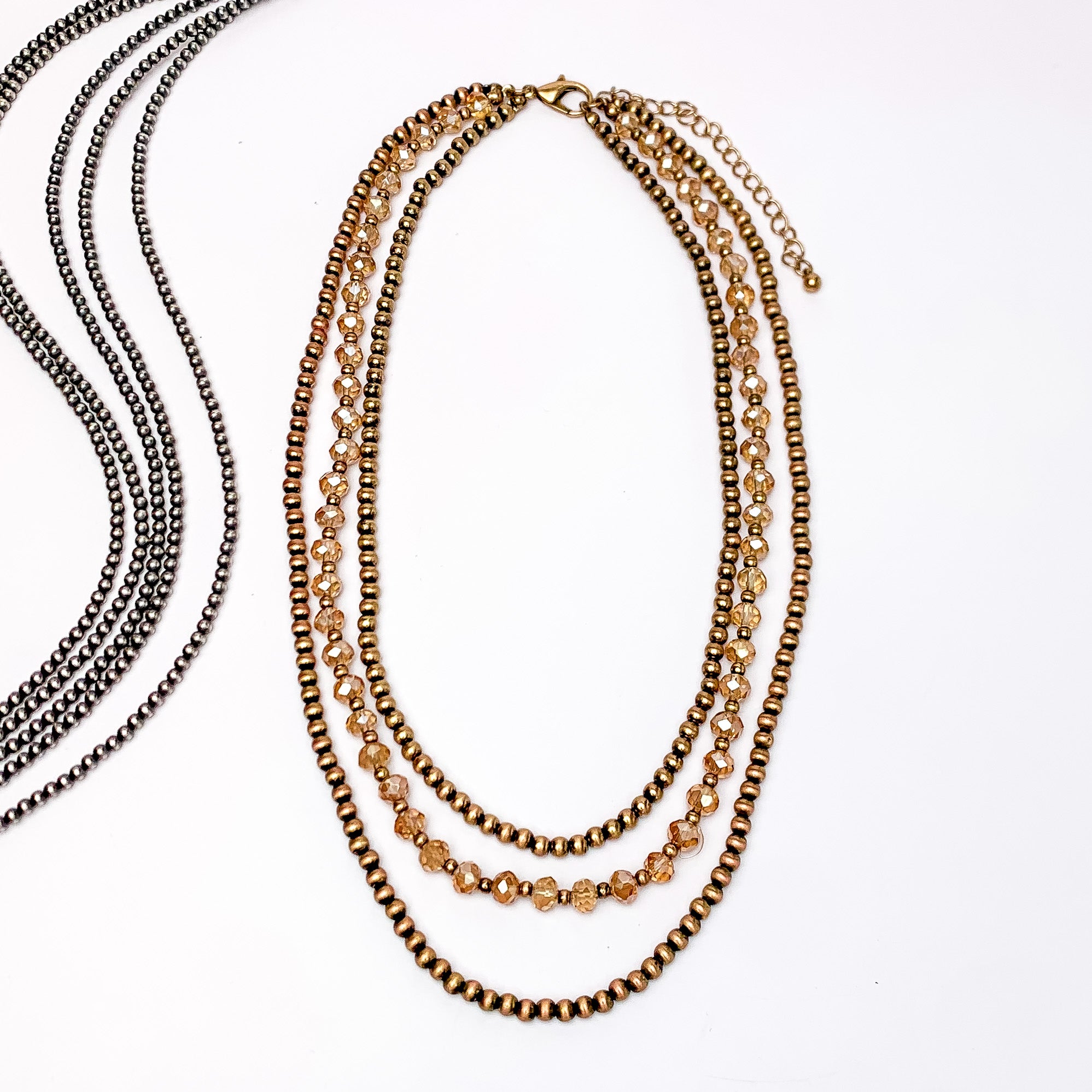 Wild Western Faux Navajo Three Strand Pearl Necklace in Copper Tone. Pictured on a white background with long beads on the left side of the picture.