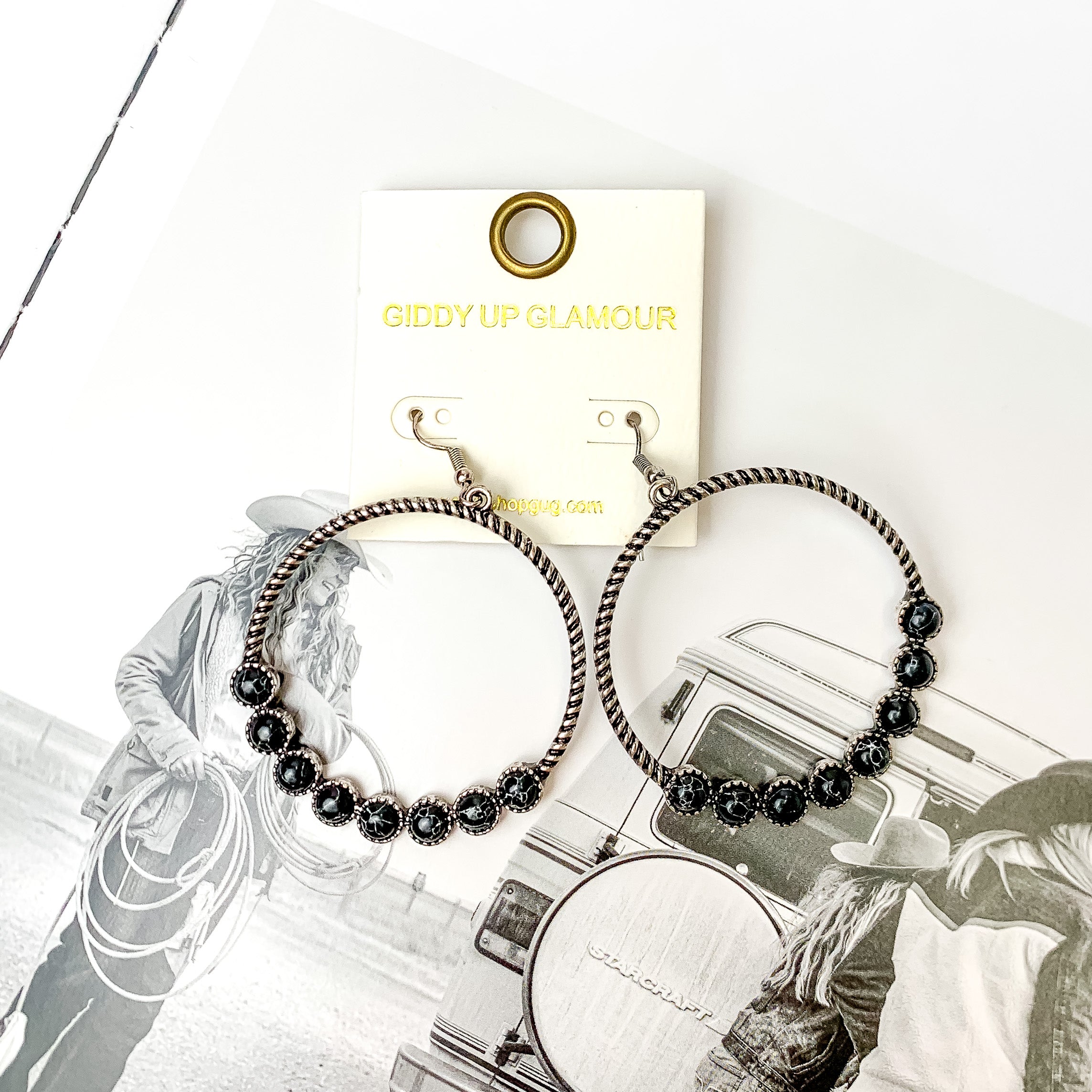 Forever Twisted Hoop Earrings with Stones in Black. Pictured on a book with a western picture on the page.