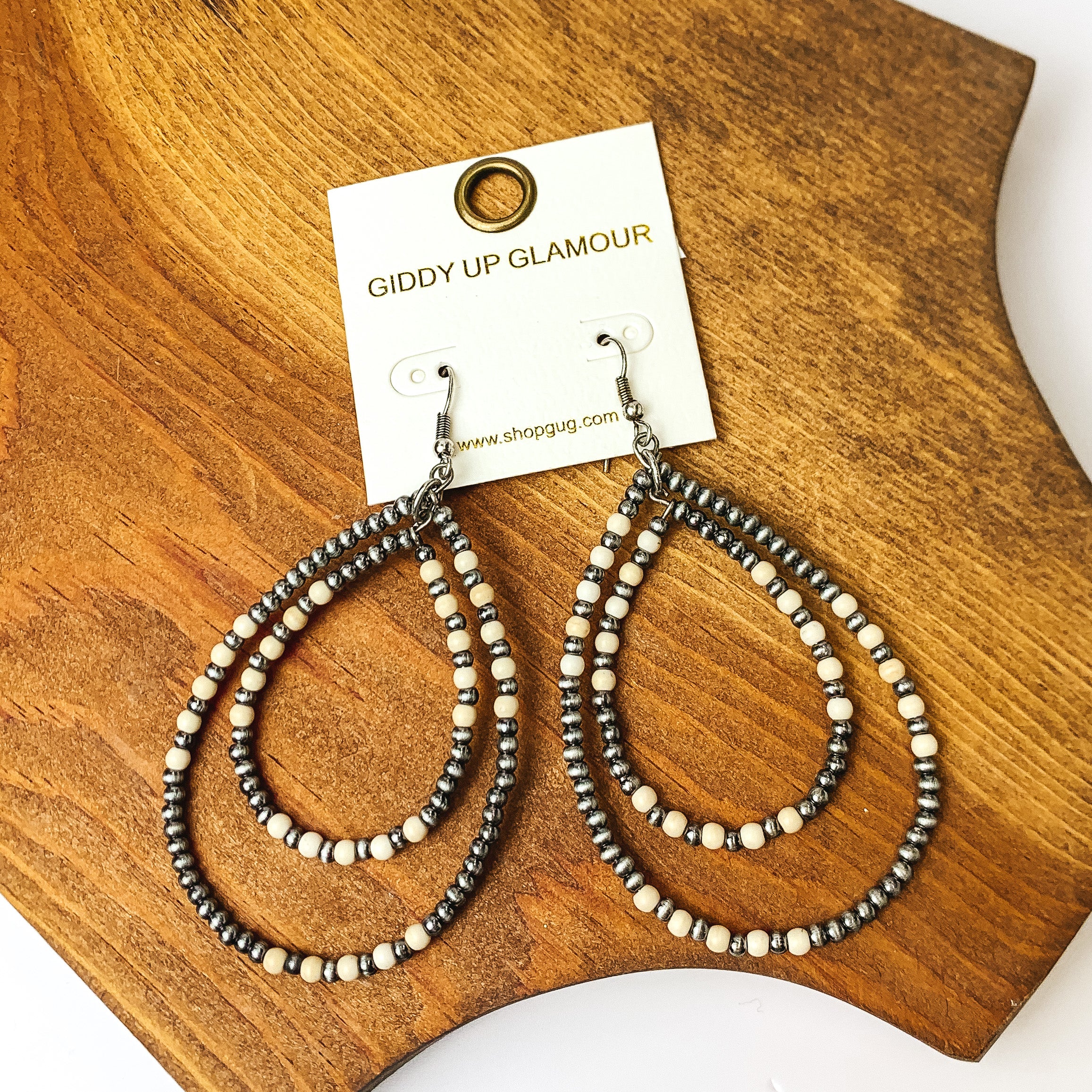 Beaded Open Double Drop Earrings in Silver Tone and Ivory. Pictured on a wood piece.