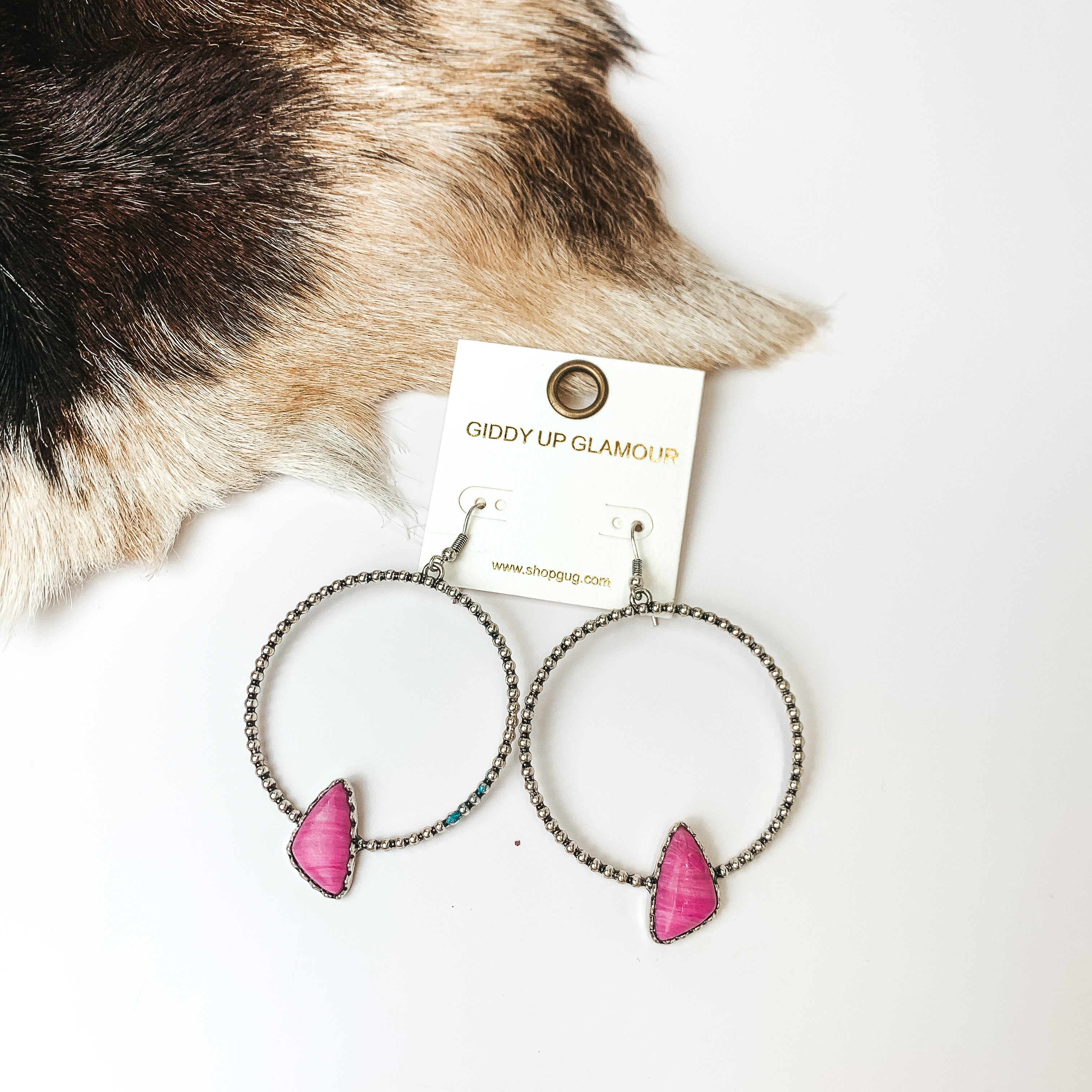 Silver Tone Textured Hoop Earring with Pink Stone. Pictured on a white background with faux animal fur in the top left.