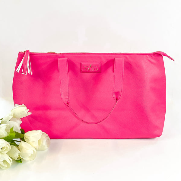 Hollis brand large overnight bag in hot pink. Pictured on a white background with white flowers in the bottom left corner.