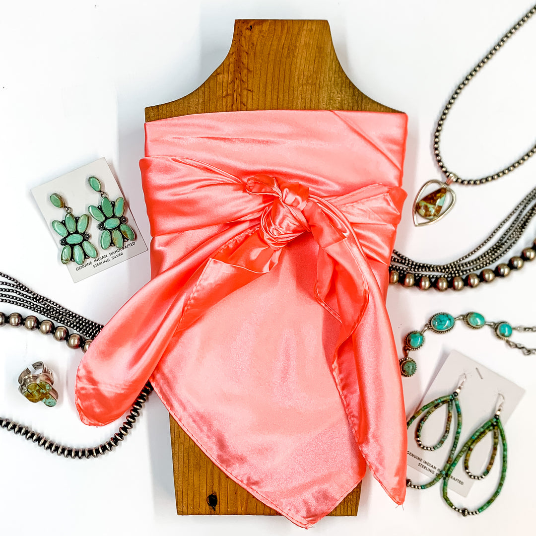 Solid colored scarf in Peach. Scarf is tied around a wooden piece. The scarf and piece of wood is pictured on a white background with Navajo jewelry spread out around it.