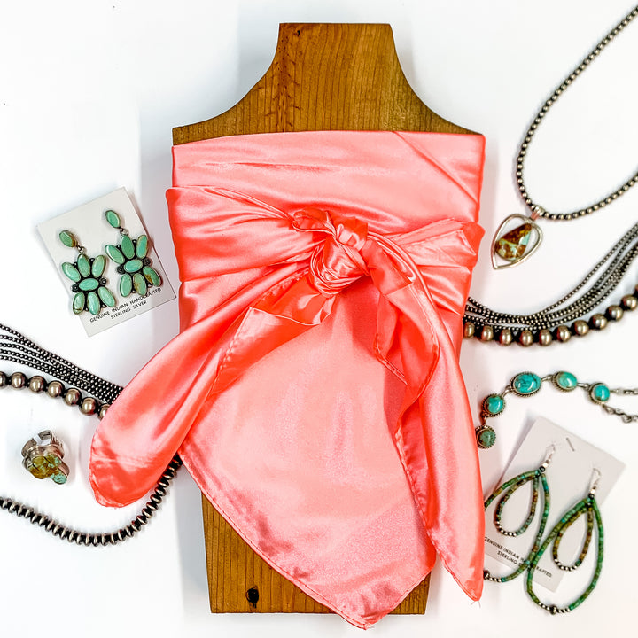 Solid colored scarf in Peach. Scarf is tied around a wooden piece. The scarf and piece of wood is pictured on a white background with Navajo jewelry spread out around it.