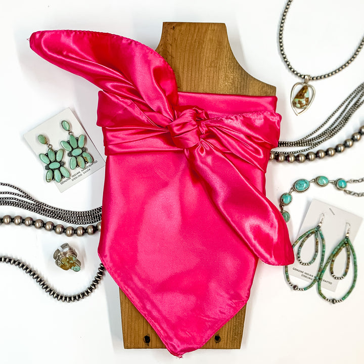 Solid colored scarf in Hot Pink. Scarf is tied around a wooden piece. The scarf and piece of wood is pictured on a white background with Navajo jewelry spread out around it.