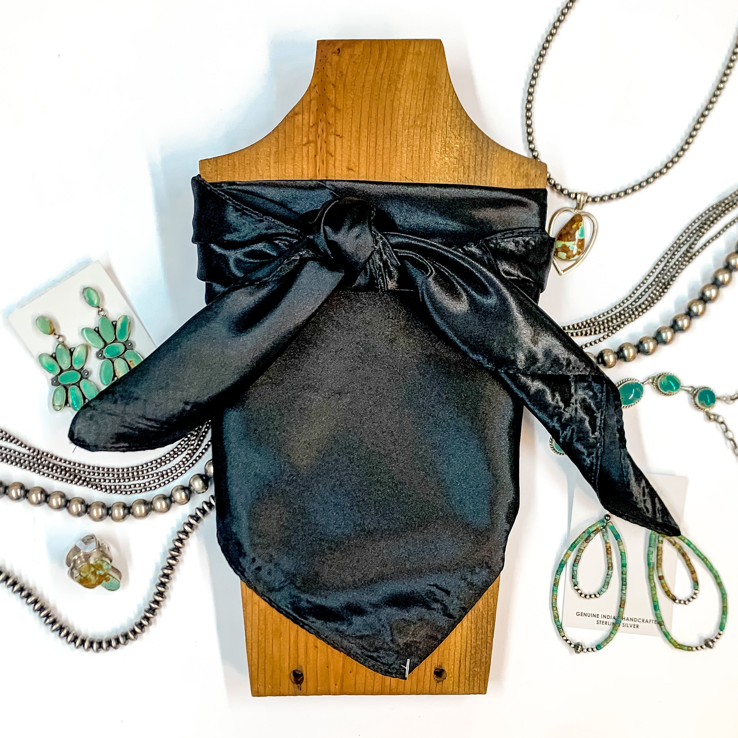 Solid colored scarf in Black. Scarf is tied around a wooden piece. The scarf and piece of wood is pictured on a white background with Navajo jewelry spread out around it.