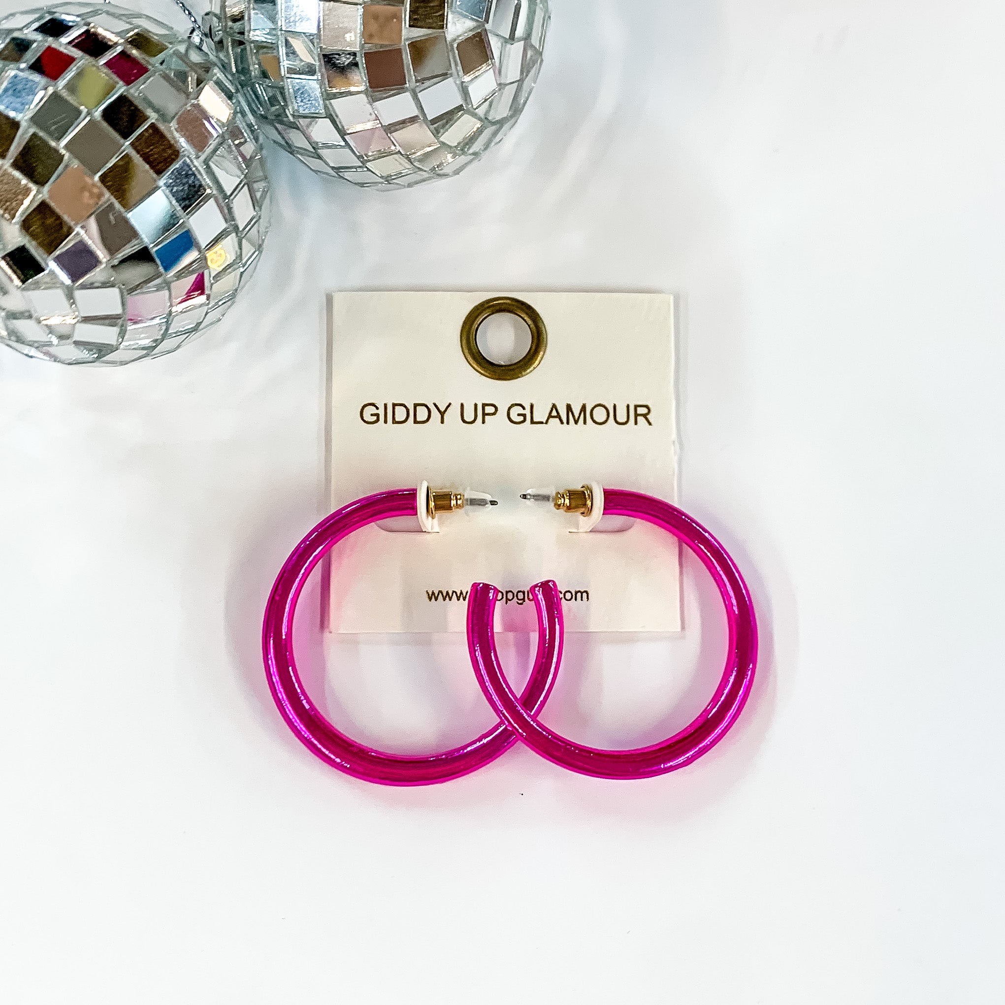 Light up Medium Neon Hoop Earrings in Hot Pink. Pictured on a white background with disco balls in the top left corner.