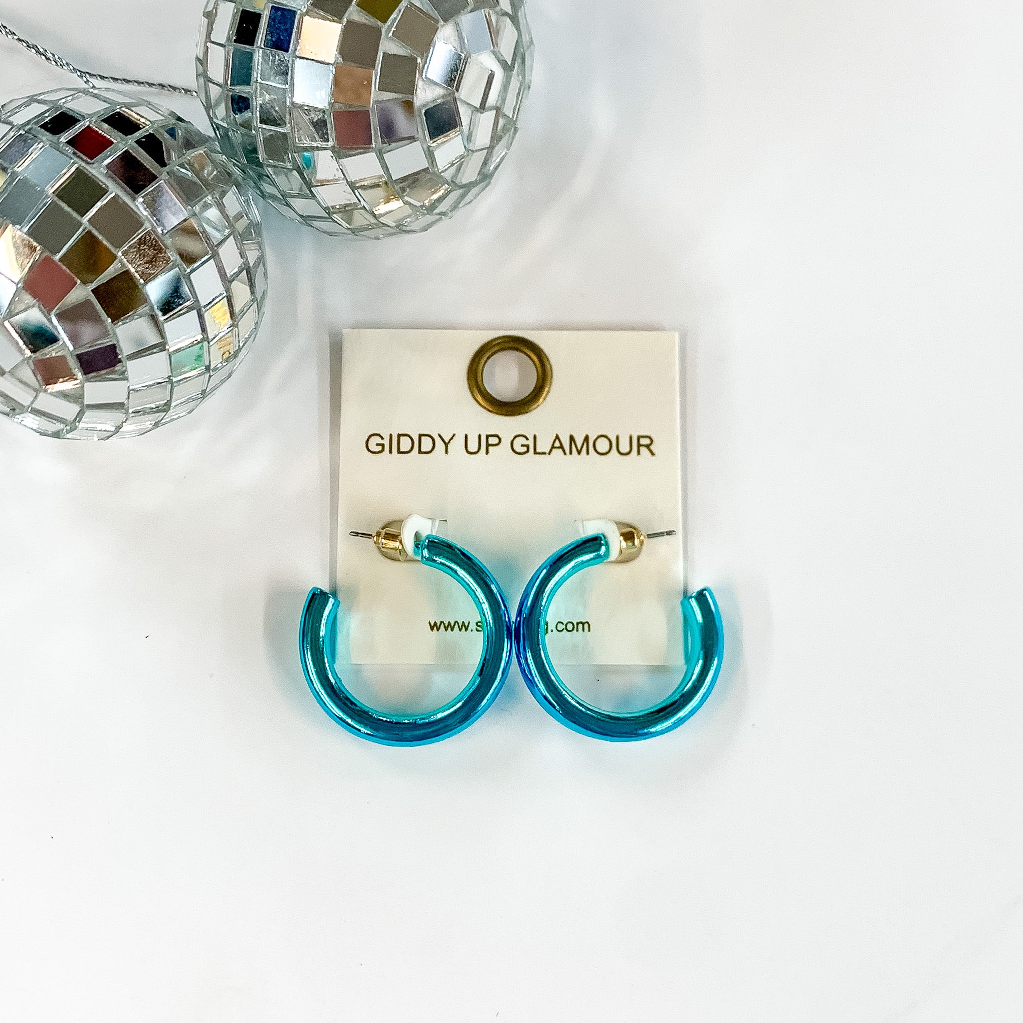 Light Up Small Neon Hoop Earrings In Blue. Pictured on a white background with disco balls in the top left corner.