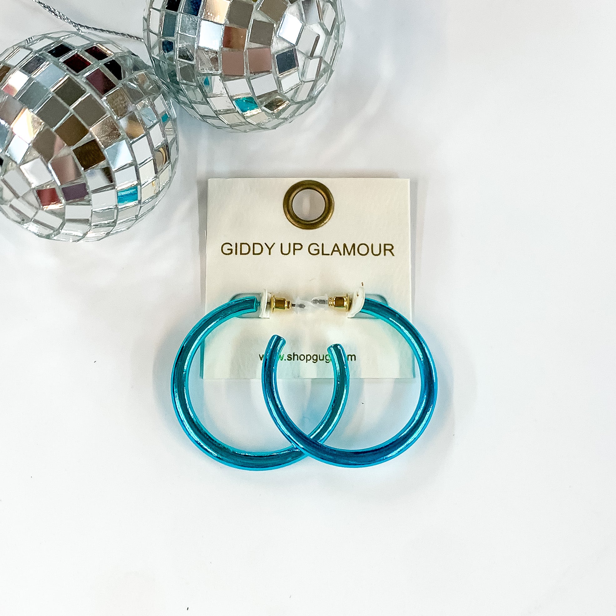 Light Up Medium Neon Hoop Earrings In Blue. Pictured on a white background with disco balls in the top left corner.