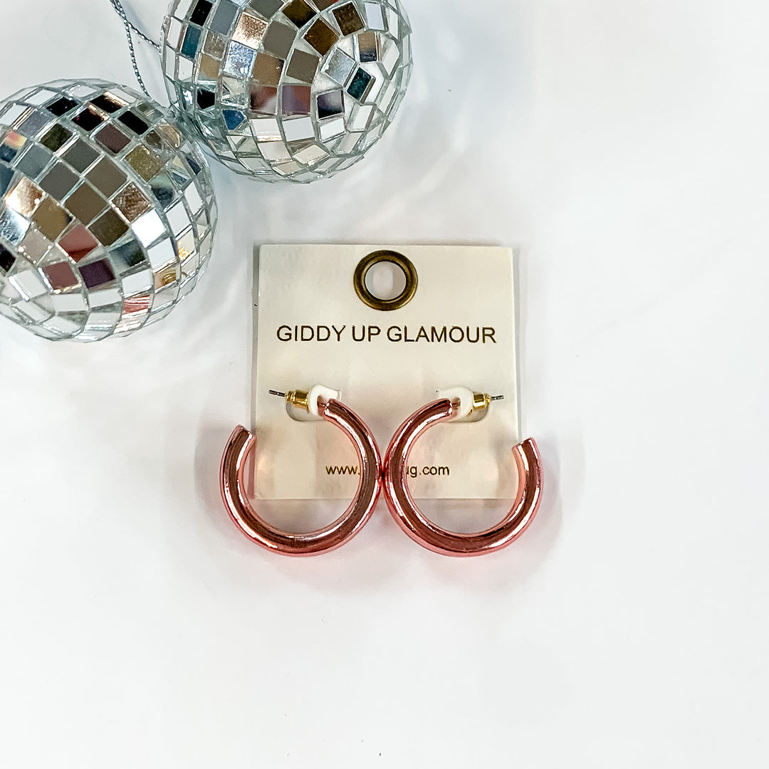 Light Up Small Neon Hoop Earrings In Light Pink. Pictured on a white screen with disco balls in the top left corner.