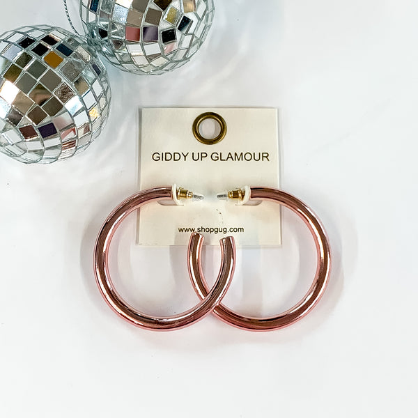 Light Up Large Neon Hoop Earrings In Light Pink. Pictured on a white background with disco balls in the top left corner.