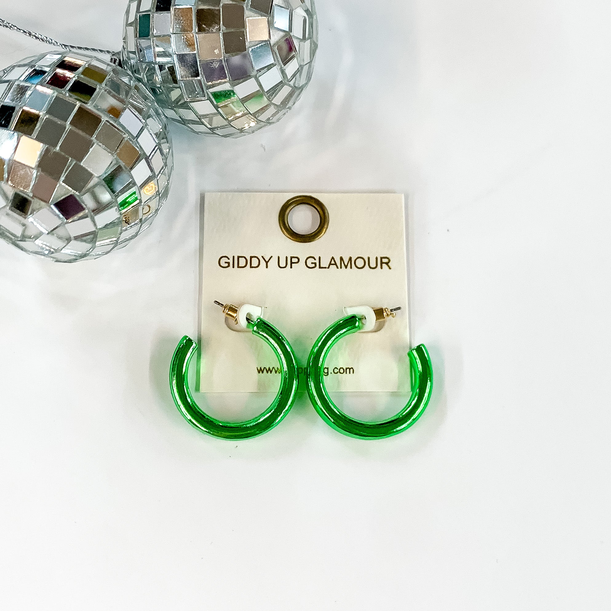 Light Up Small Neon Hoop Earrings In Green. Pictured on a white background with disco balls in the top left corner.