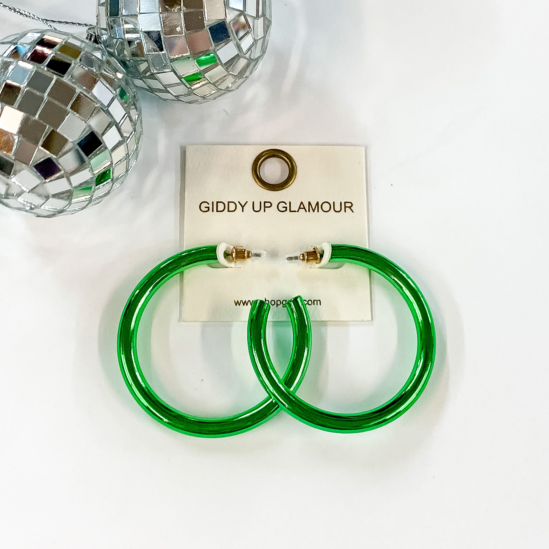 Light Up Large Neon Hoop Earrings In Green. Pictured on a white background with disco balls in the top left corner.