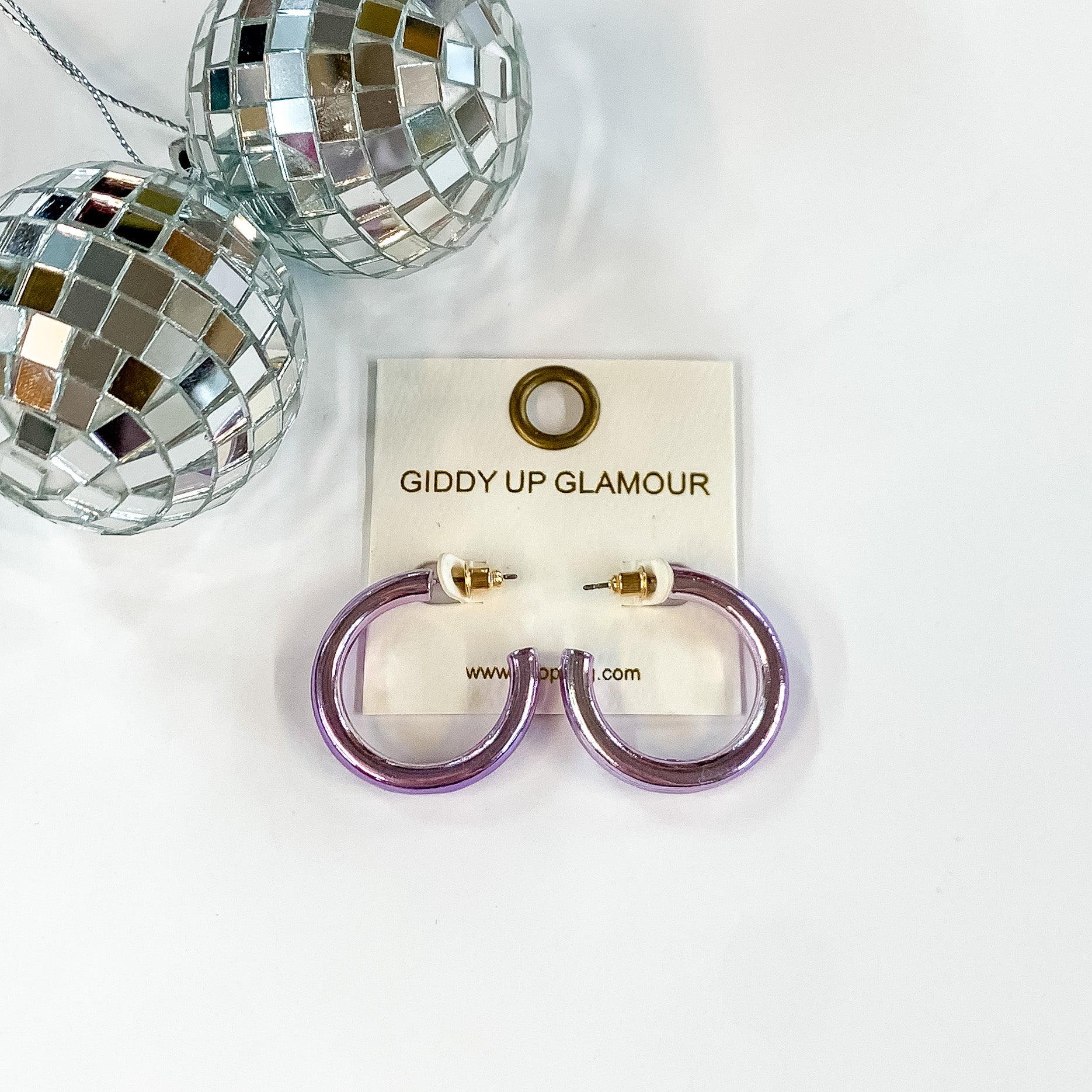 Light Up Small Neon Hoop Earrings In Lavender. Pictured on a white background with disco balls in the top left corner. 