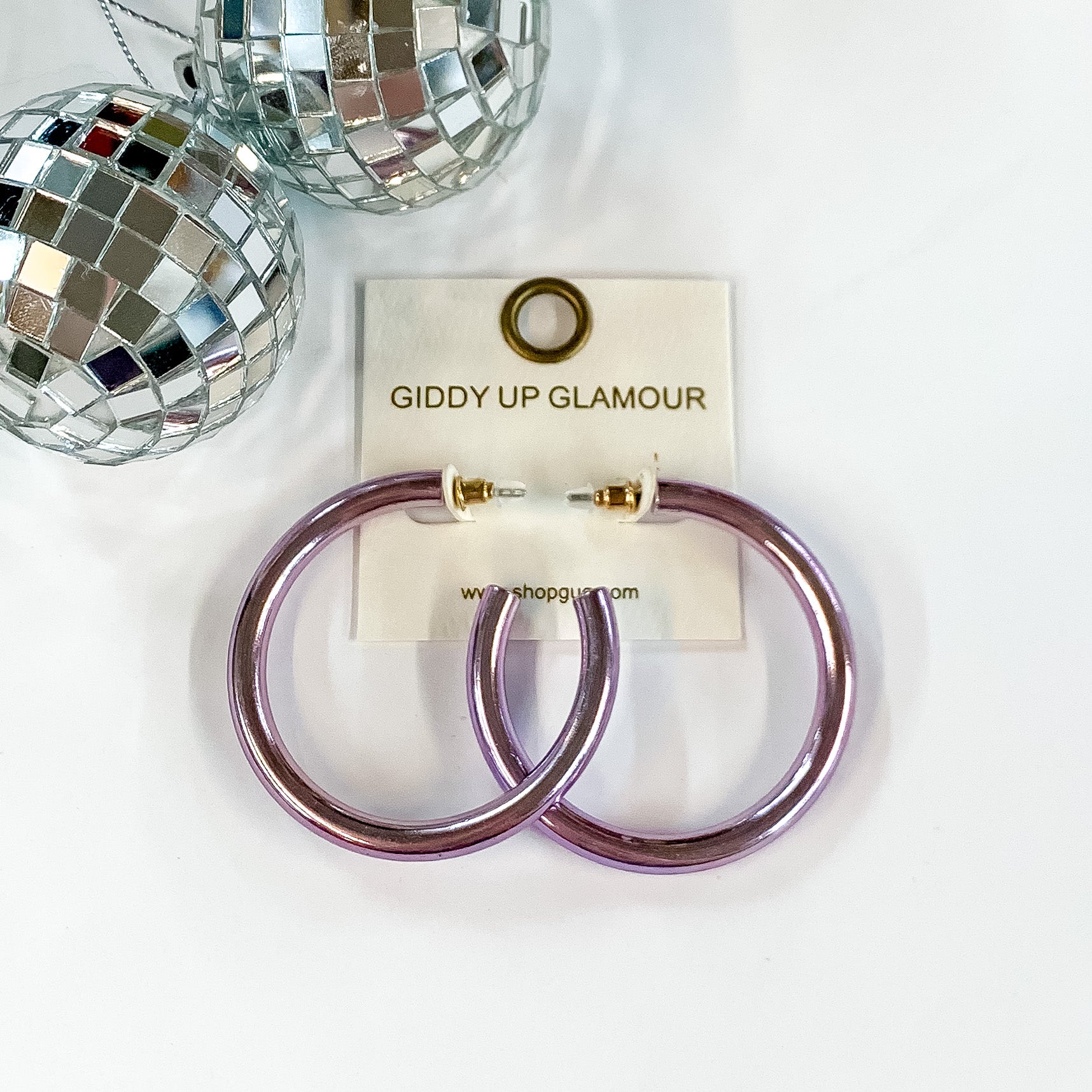 Light Up Large Neon Hoop Earrings In Lavender. Pictured on a white background with disco balls in the top left corner.