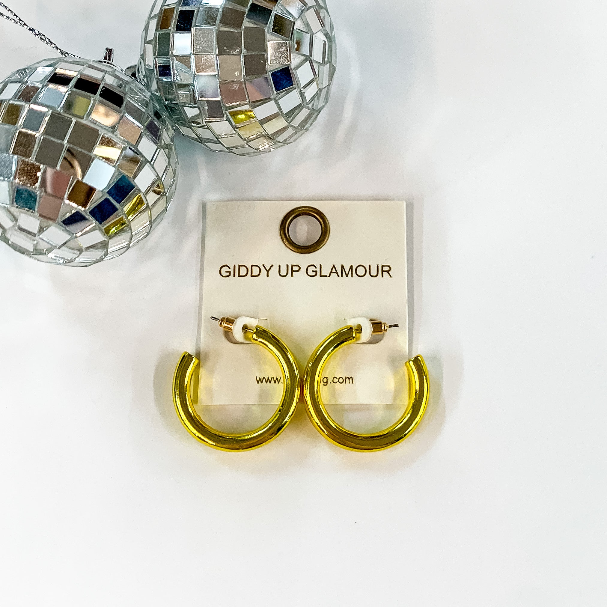 Light Up Small Neon Hoop Earrings In Yellow. Pictured on a white background with disco balls in the top left corner.