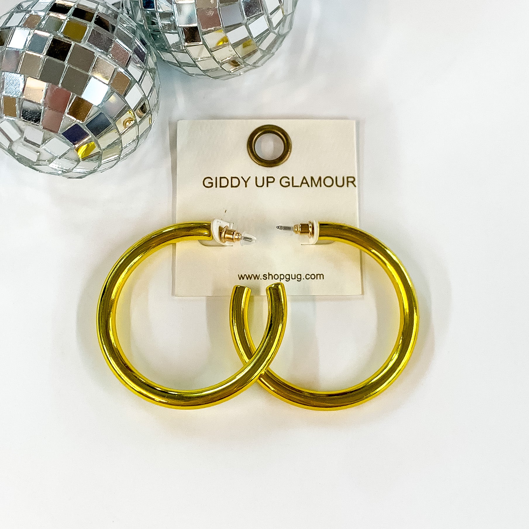 Light Up Large Neon Hoop Earrings In Yellow. Pictured on a white background with a disco ball in the top left corner.