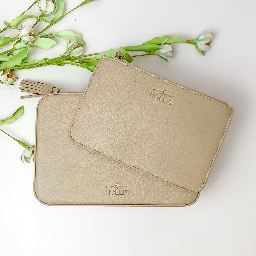 Nude jewelry totes pictured on top of each other. These bags are pictured on a white background with green and white flowers in the background. 