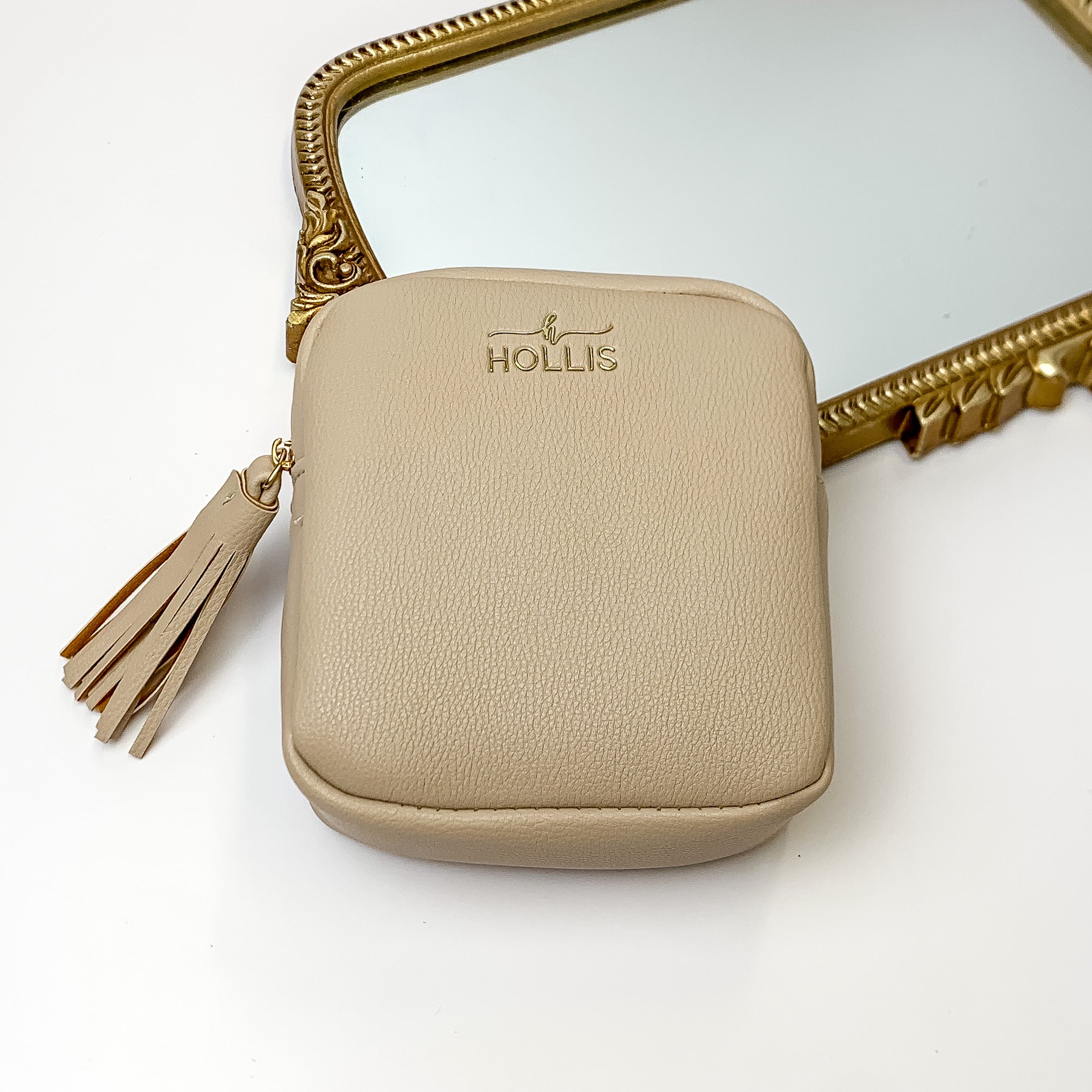 Nude square pouch that is pictured in front of a gold mirror on a white background. 