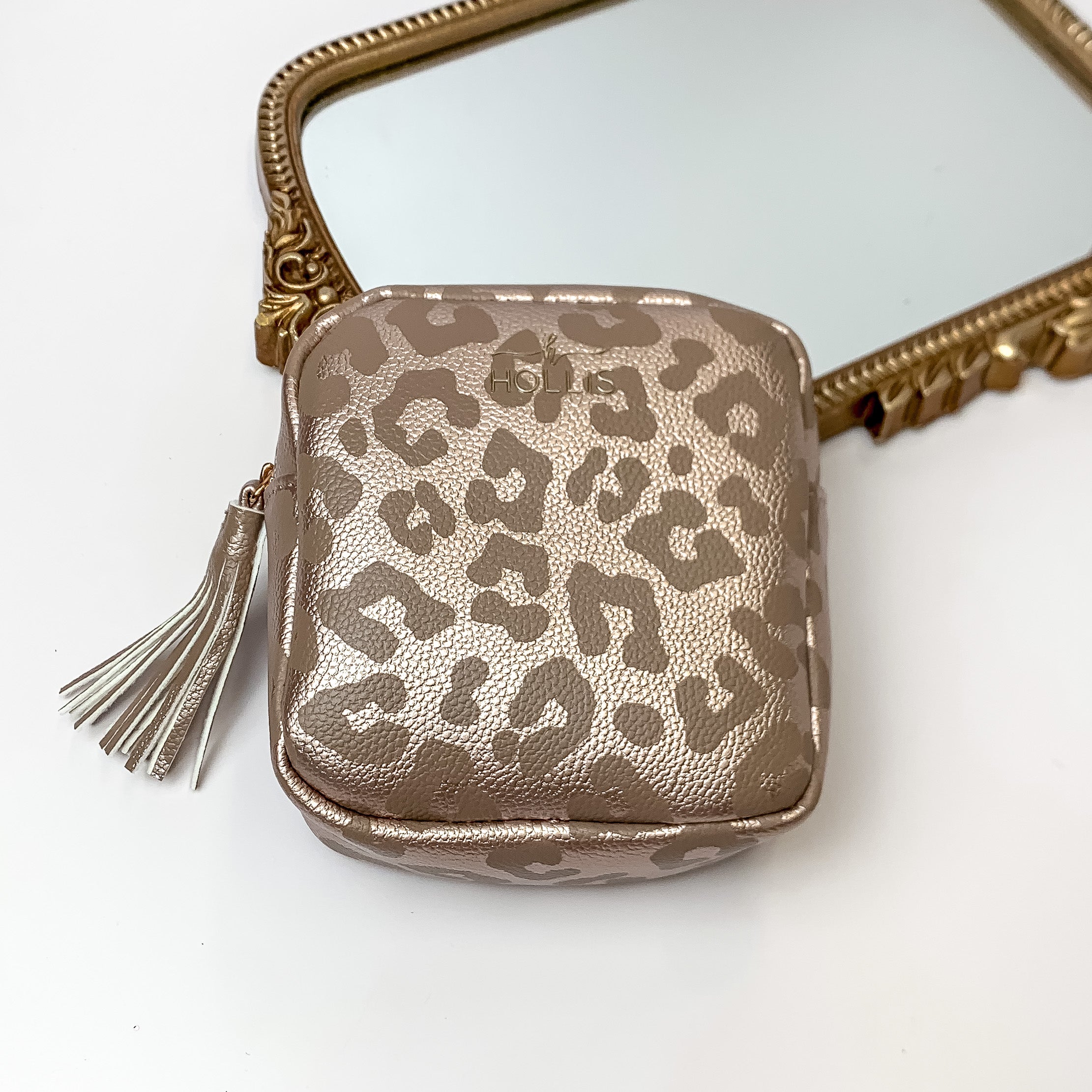 Metallic mocha square pouch with a leopard print design that is pictured in front of a gold mirror on a white background. 