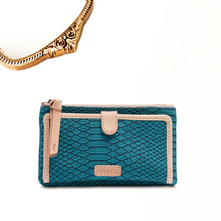 A solid white background with a gold mirror. Indy slim wallet is a turquoise, reptile-inspired textured and genuine leather details. The interior has a Full-length zipper compartment, 12 card slots, ID window, and 4 slide pocket compartments with snap closure.