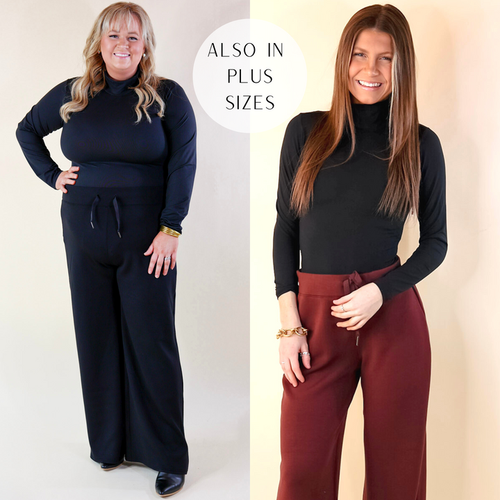 Model is wearing a black turtleneck long sleeve bodysuit. Model has this paired with maroon Spanx pants, white shoes, and Sorelli gold jewelry.