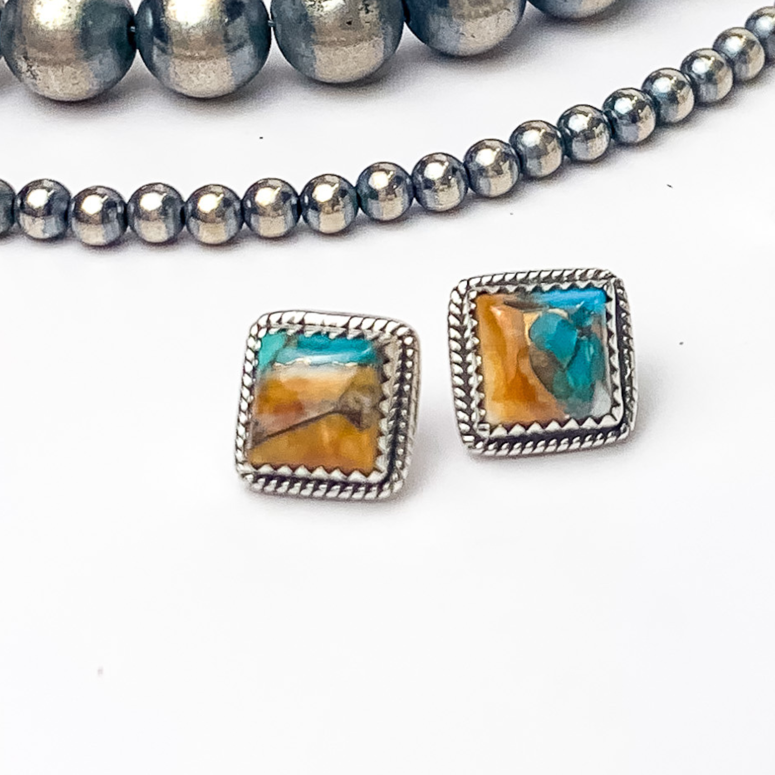 In the picture are handmade sterling silver square stud earrings with spiny turquoise remix stones with a white background