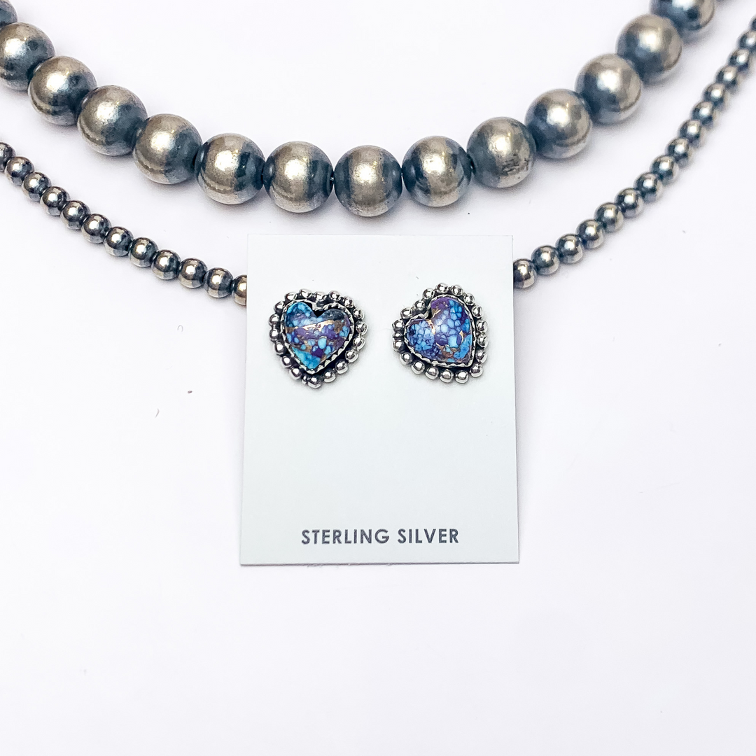 In this picture are heart shaped stud earring with a purple mojave color with a white background