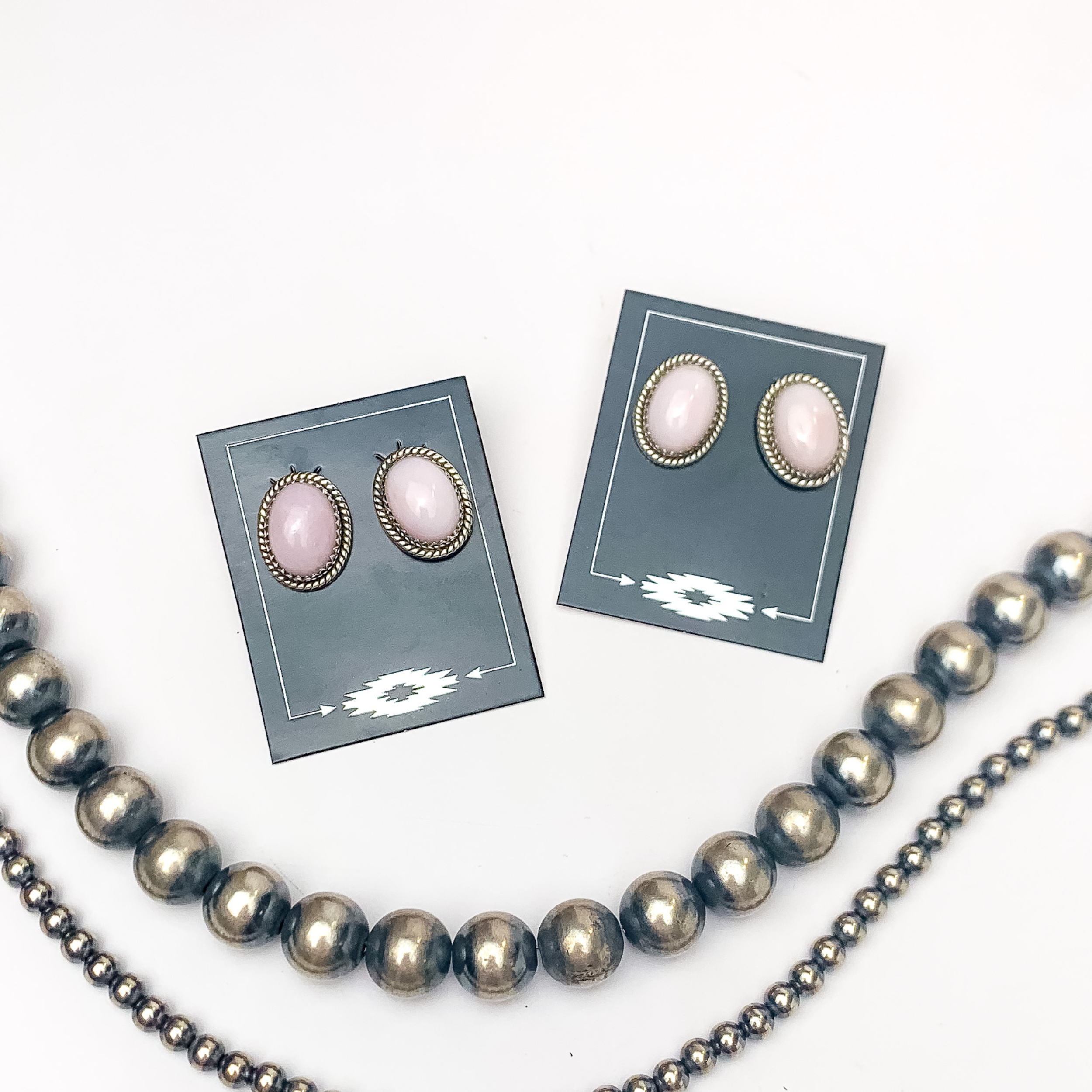 In the picture are handmade sterling silver oval shaped stud earrings with a pink opal color with a white background 