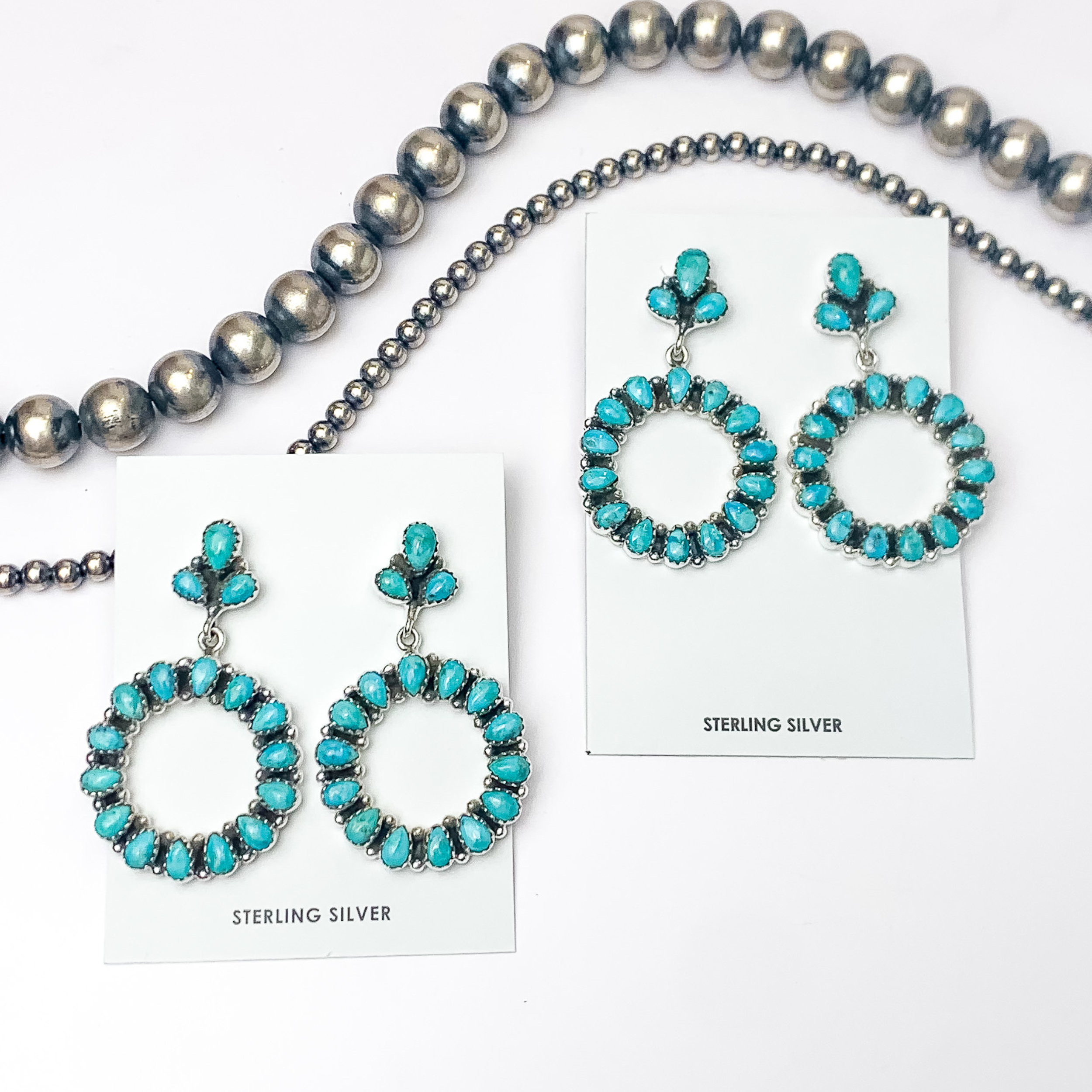 In the picture are stud cluster earrings with a circle drop in the color kinsman turquoise with a white background