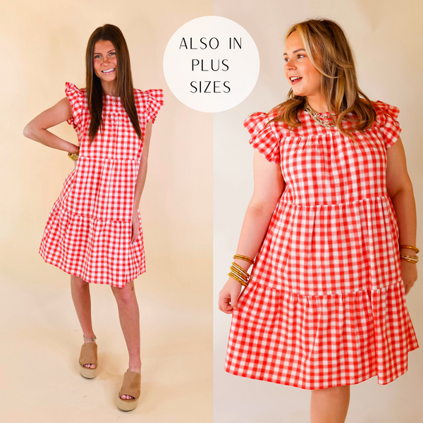 Model is wearing a red and white gingham dress with ruffle cap sleeves and a tiered body. Model has it paired with tan wedges and gold jewelry.
