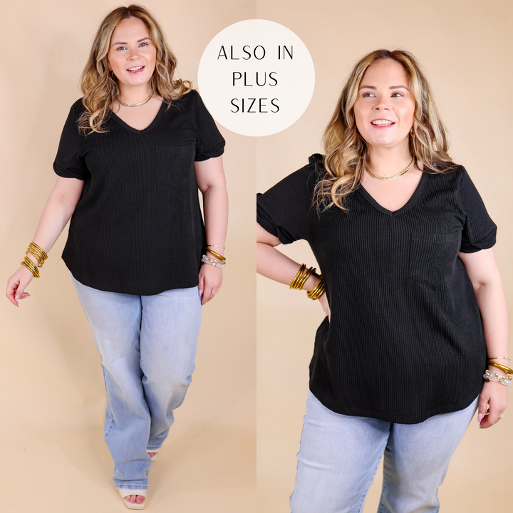 Model is wearing a short sleeve ribbed top with a v neckline and chest pocket. Model has this top paired with light wash jeans, white heels, and gold jewelry.