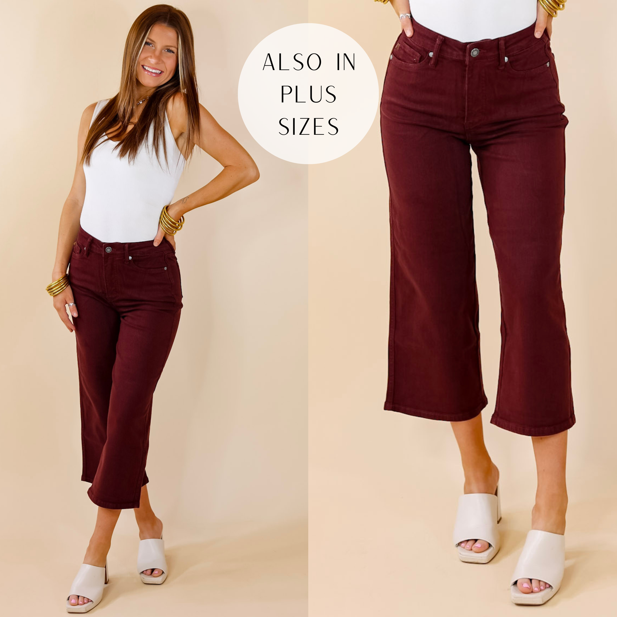 Model is wearing a pair of cropped jeans in maroon. Model has it paired with a white tank top, ivory heels, and gold jewelry.