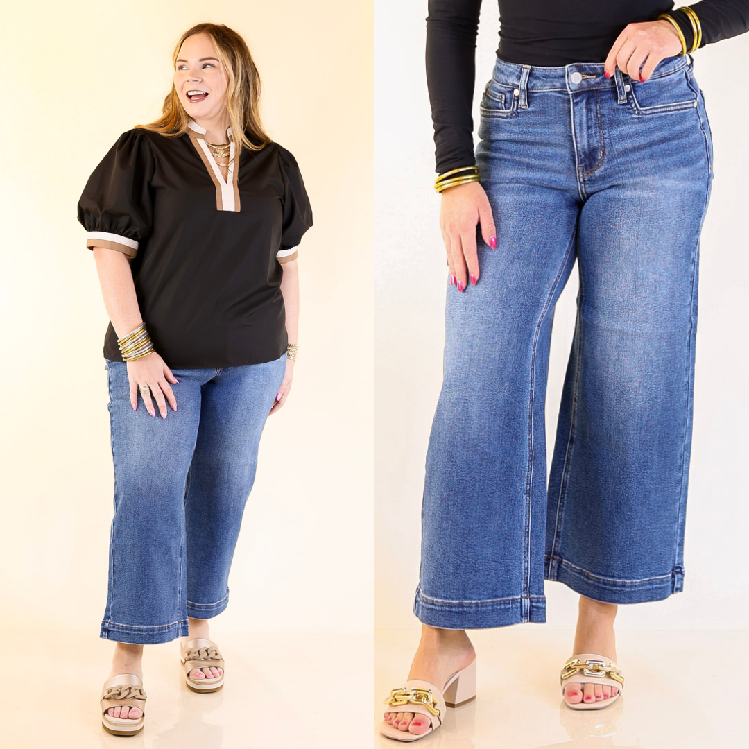 Two people wearing wide leg blue jeans with a plain background