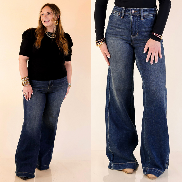 Woman wearing wide leg blue jeans with a plain background