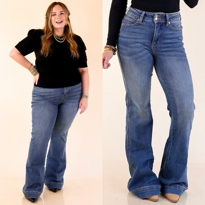 Woman wearing flare blue jeans with a plain background