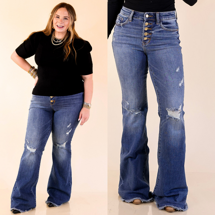 Woman wearing blue distressed flared jeans with a plain background