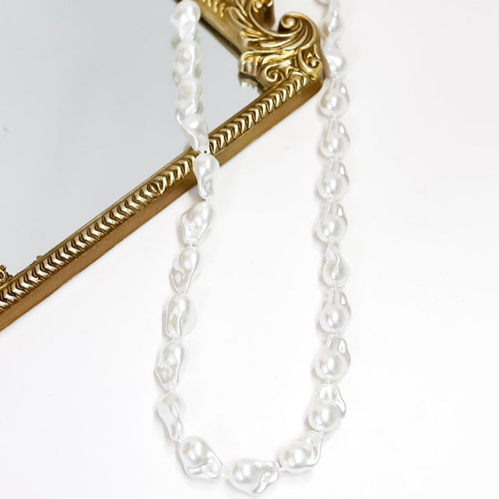 Decorative mirror with gold frame and chain on a white background