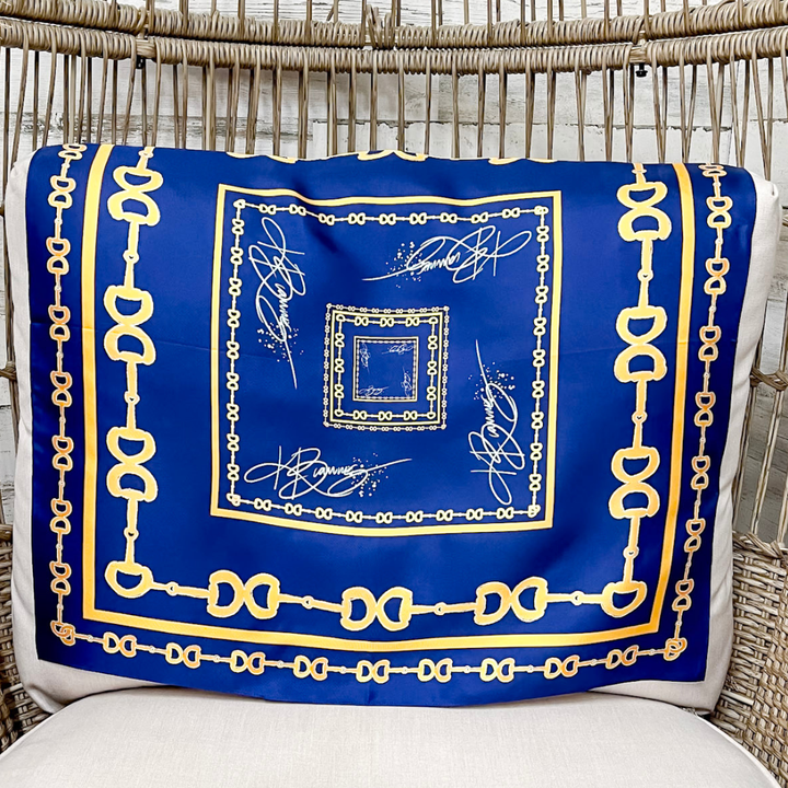 Blue scarf with gold border and patterns draped over a wicker chair.