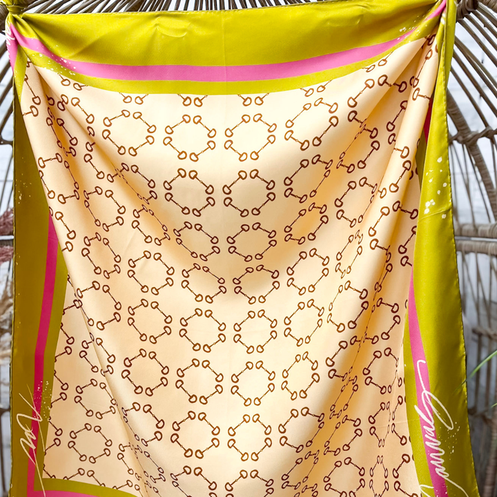 Yellow and pink fabric with a pattern, possibly a scarf or shawl, draped over a natural background.