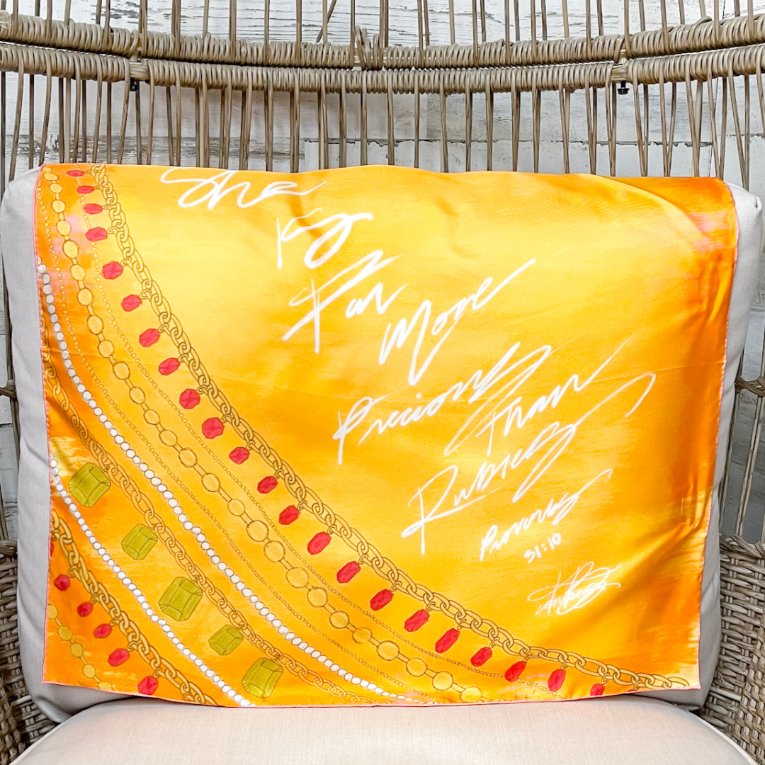 Yellow scarf with decorative border and text draped over a chair