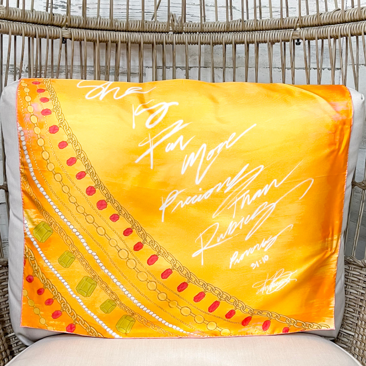 Yellow scarf with decorative border and text draped over a chair
