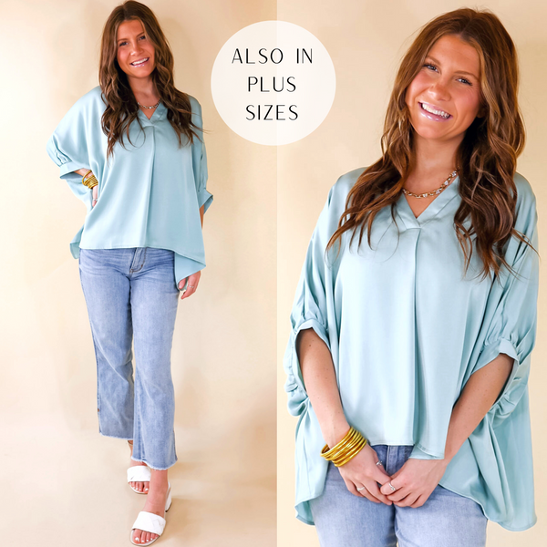 A flowy oversized light blue blouse featuring cuffed sleeves, a V neckline, and a light silky fabric.