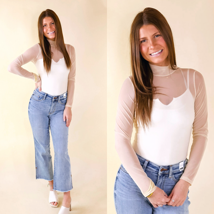 Model is wearing an ivory bodysuit with long sleeves and a mock neckline.