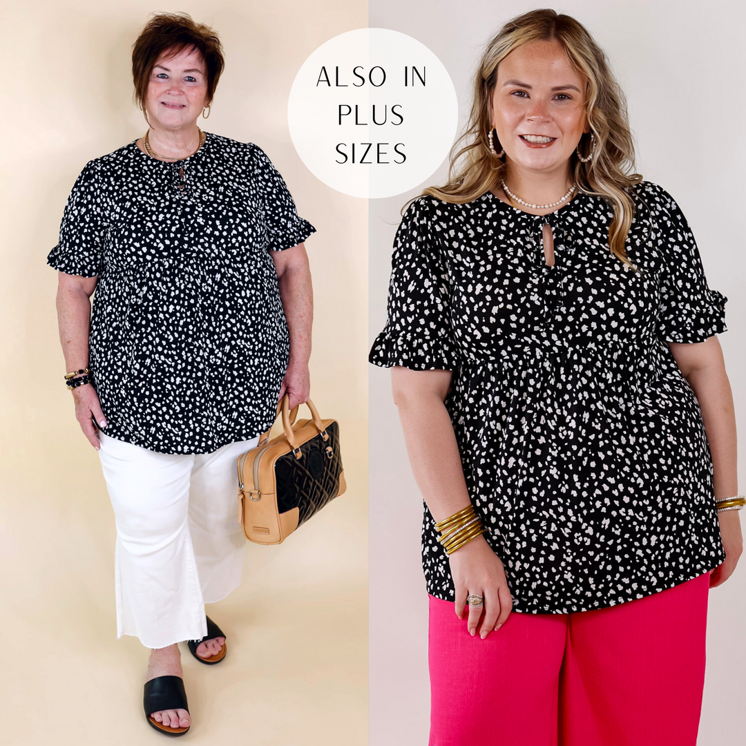 Model is wearing a black babydoll top with short sleeves, a keyhole and tie neckline, and a white leopard print all over.