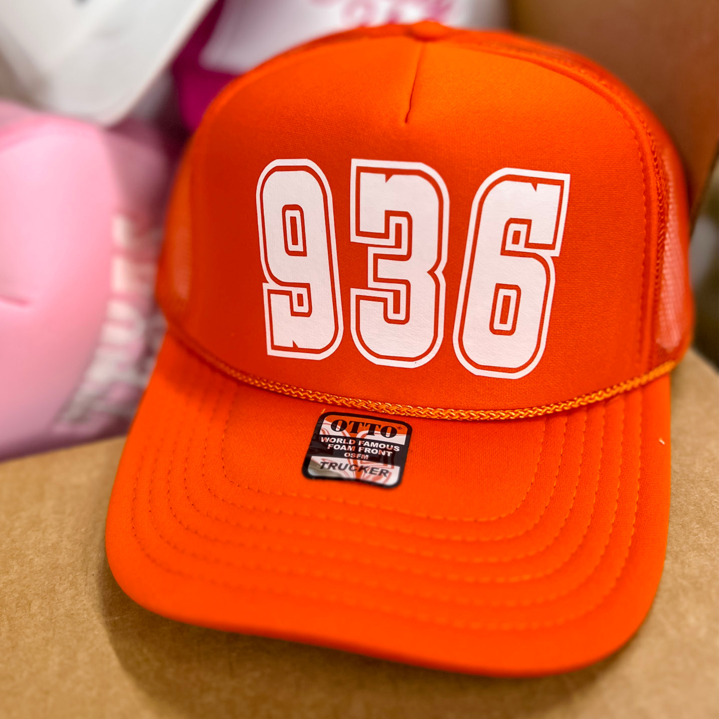 Photo features an orange trucker hat with the letters 936 in large white font on the front.