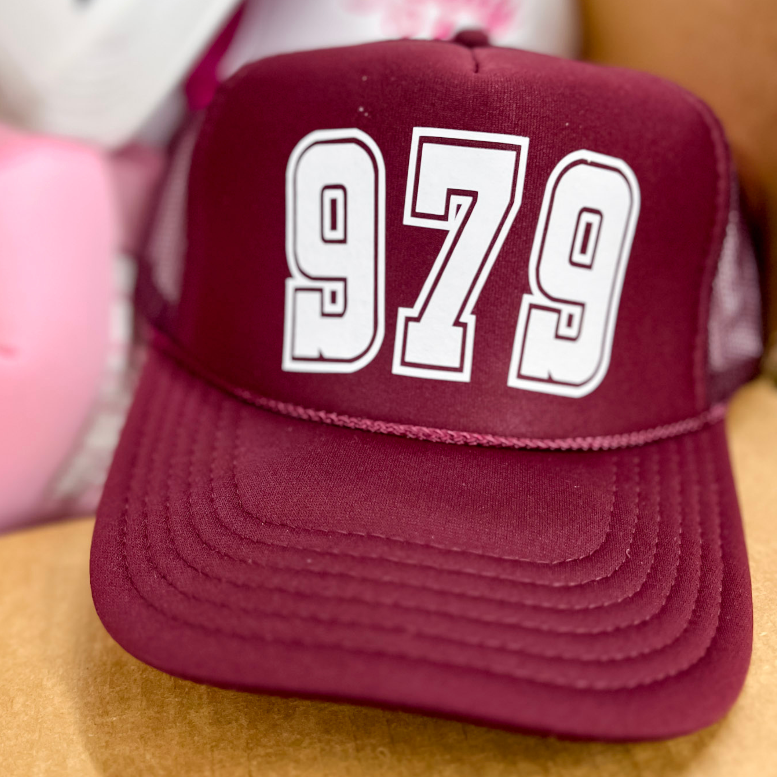 Photo features a maroon trucker hat with the numbers 979 in large white font on the front.