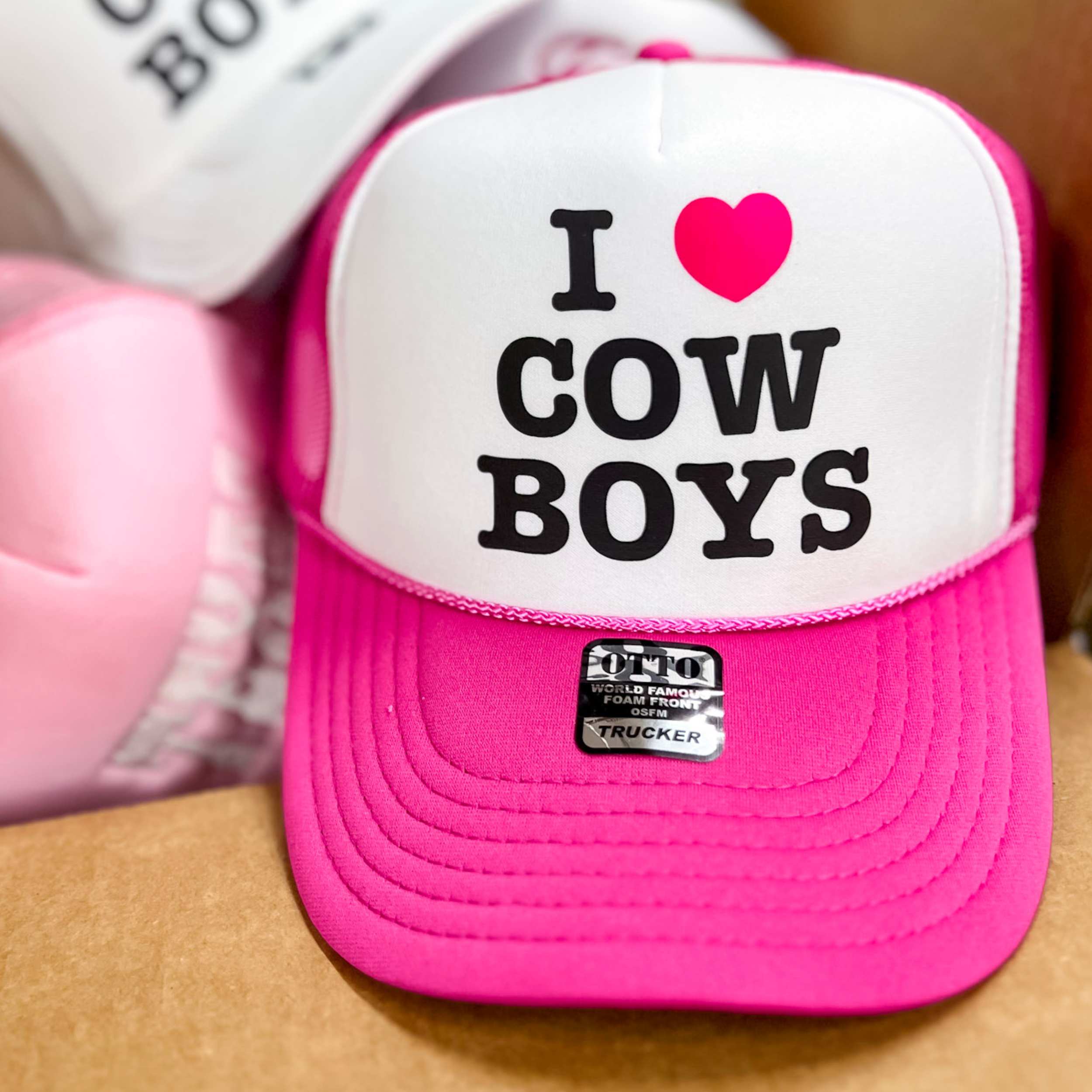 Photo features a hot pink and white trucker hat with "I heart Cowboys" on the front.
